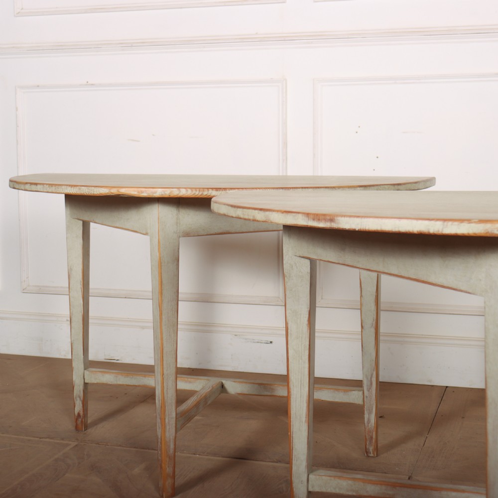 A pair of antique Swedish semi-circular console tables featuring a distressed pale grey painted finish, simple aprons, and straight tapered legs with stretchers. View III