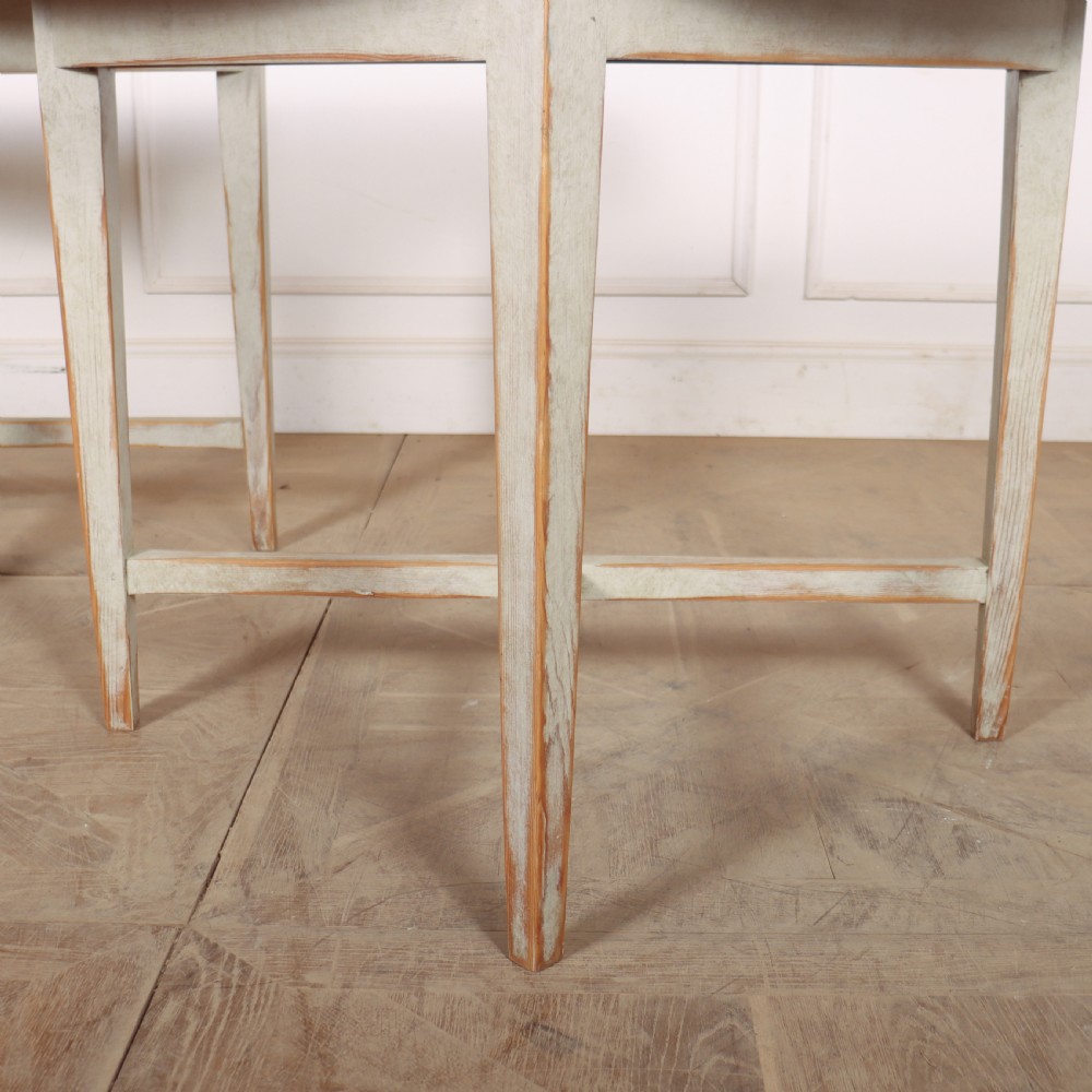 A pair of antique Swedish semi-circular console tables featuring a distressed pale grey painted finish, simple aprons, and straight tapered legs with stretchers. View V