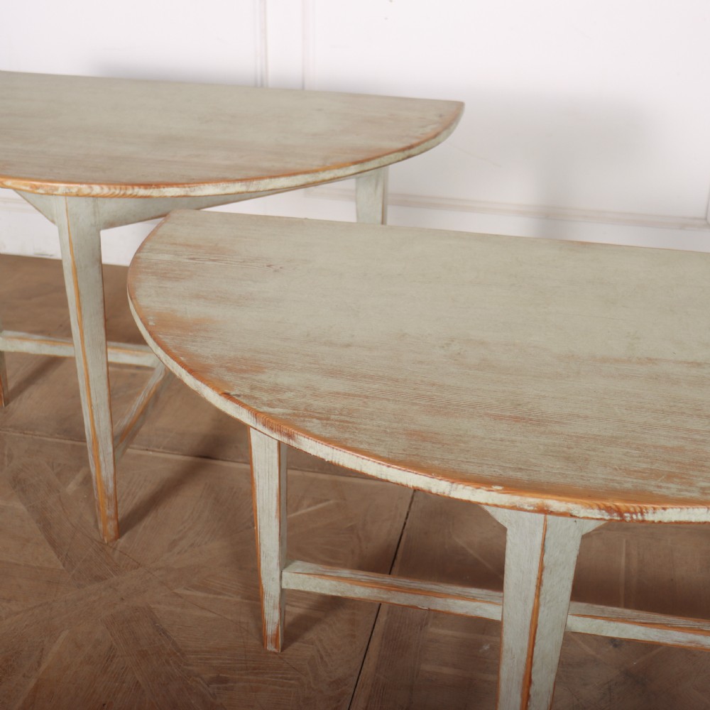 A pair of antique Swedish semi-circular console tables featuring a distressed pale grey painted finish, simple aprons, and straight tapered legs with stretchers. View VI