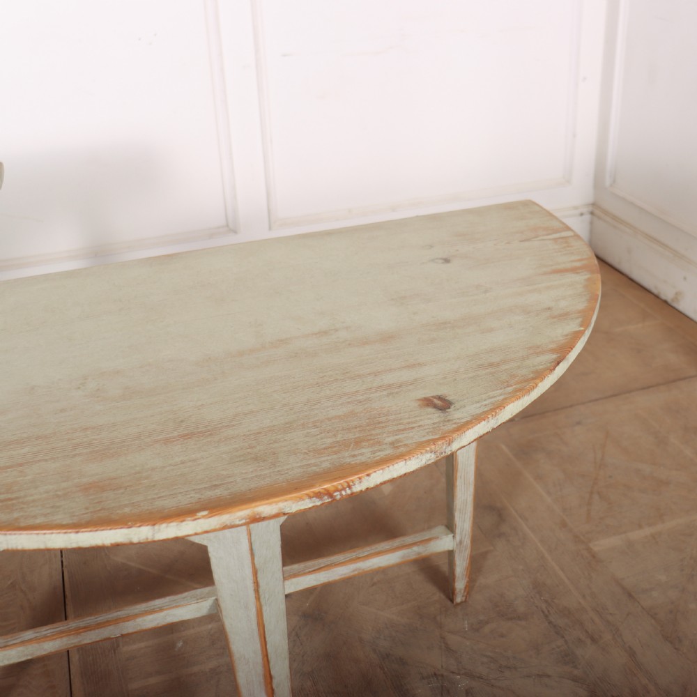A pair of antique Swedish semi-circular console tables featuring a distressed pale grey painted finish, simple aprons, and straight tapered legs with stretchers. View VII