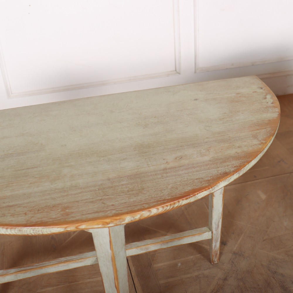 A pair of antique Swedish semi-circular console tables featuring a distressed pale grey painted finish, simple aprons, and straight tapered legs with stretchers. View IX
