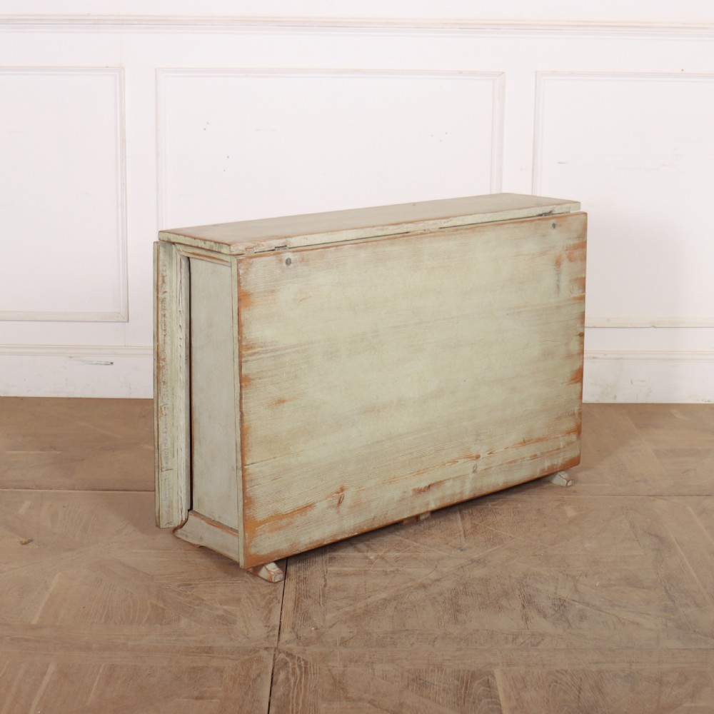 A folded Swedish slagbord drop-leaf dining table with distressed pale green paint over pine timber.