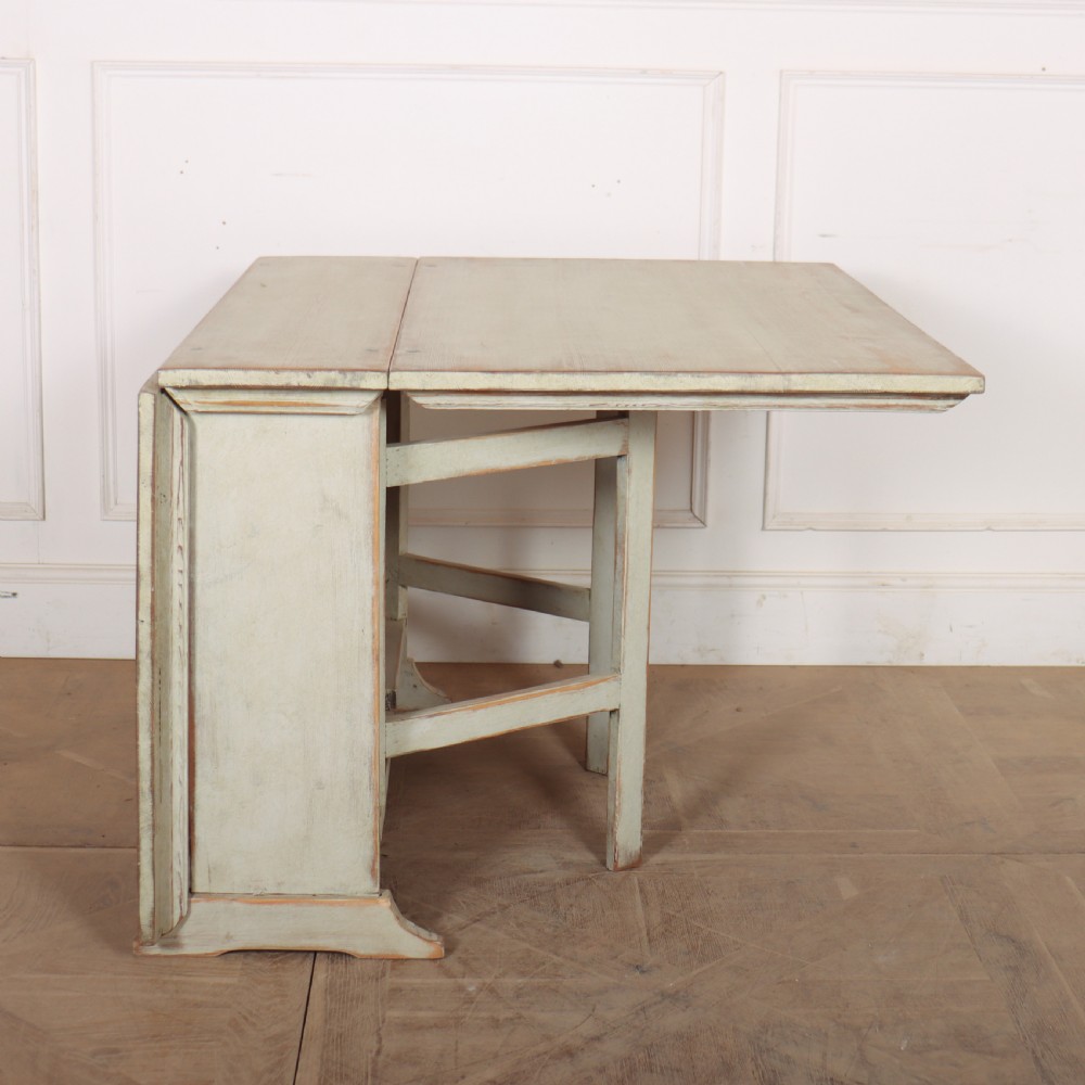 A folded Swedish slagbord drop-leaf dining table with distressed pale green paint over pine timber. View II