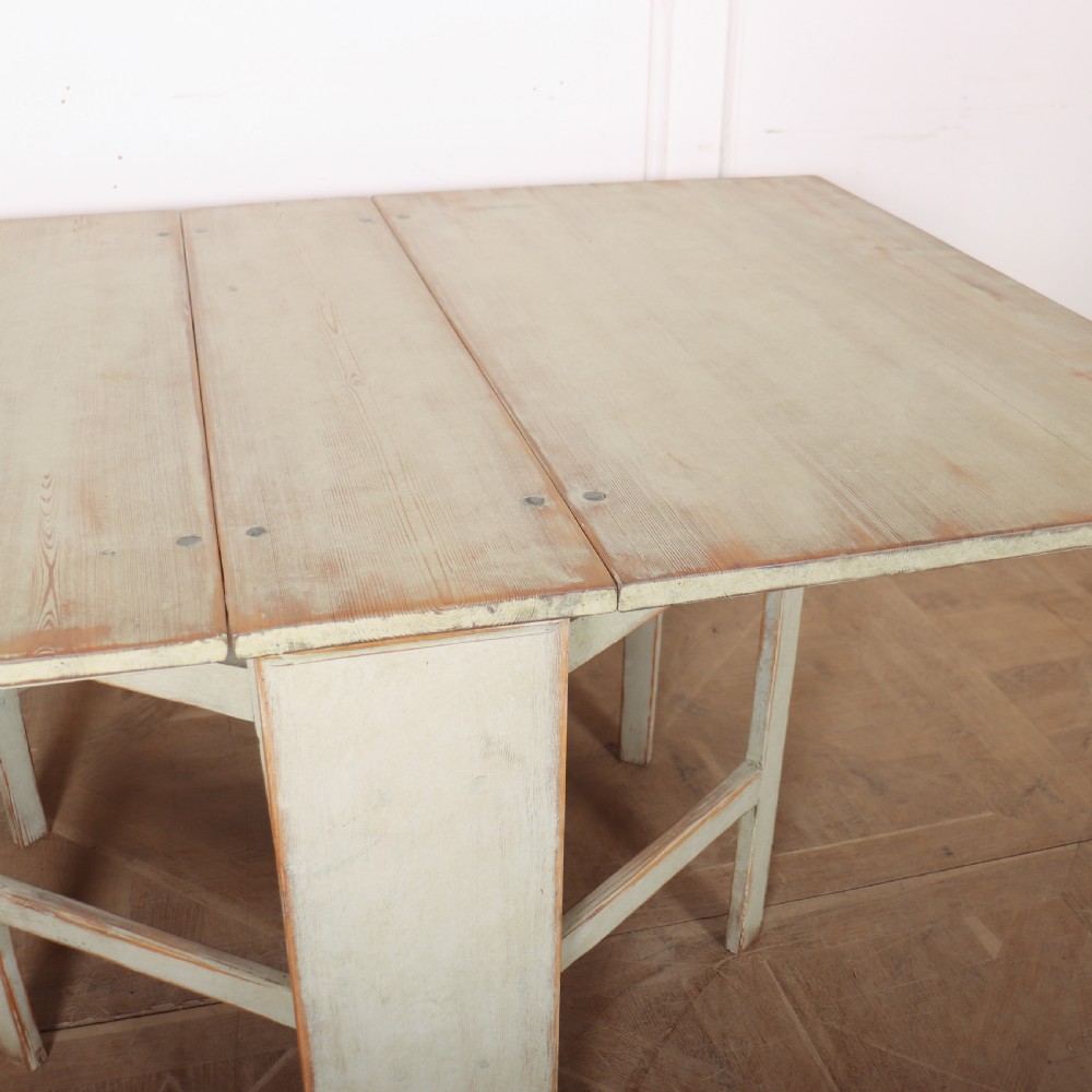 A folded Swedish slagbord drop-leaf dining table with distressed pale green paint over pine timber. View IV