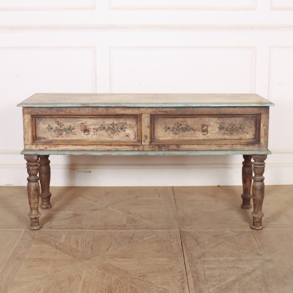 A long colonial painted wooden serving table featuring two drawers decorated with hand-painted floral motifs, brass ring handles, and four turned legs.