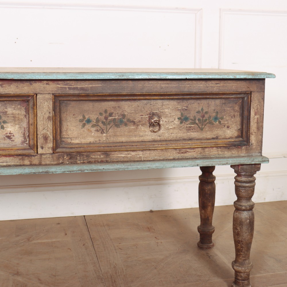 A long colonial painted wooden serving table featuring two drawers decorated with hand-painted floral motifs, brass ring handles, and four turned legs. View III