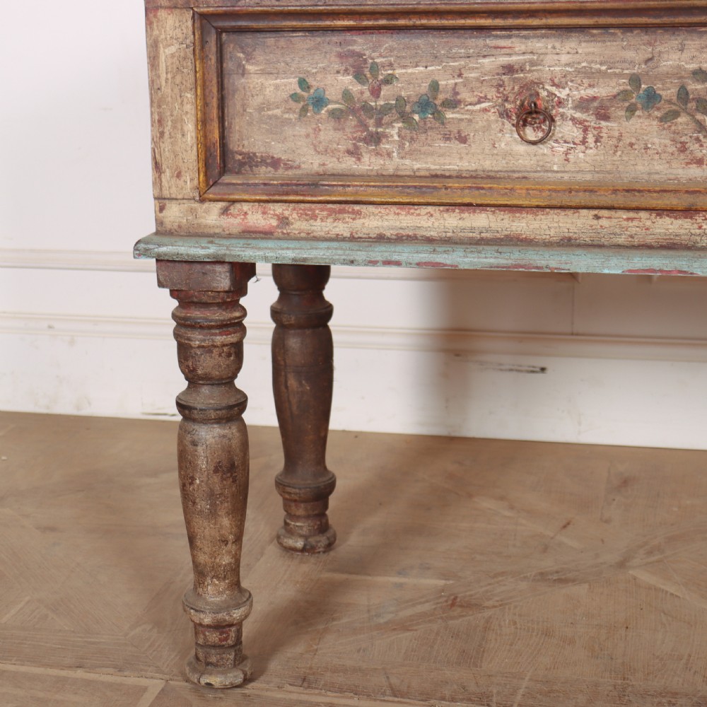 A long colonial painted wooden serving table featuring two drawers decorated with hand-painted floral motifs, brass ring handles, and four turned legs. View V