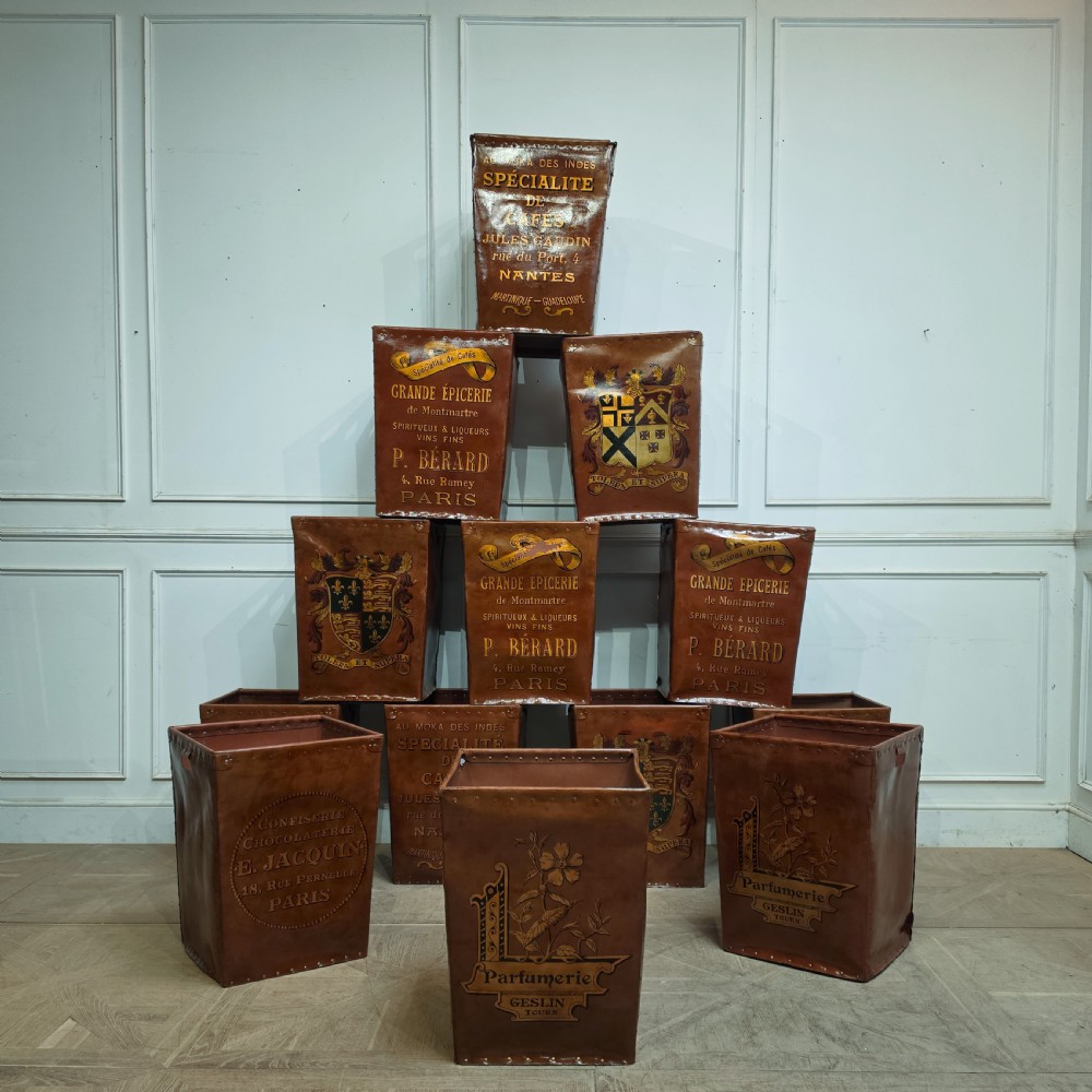 A collection of warm brown studded leather storage bins decorated with gilded French typography and heraldic crests.