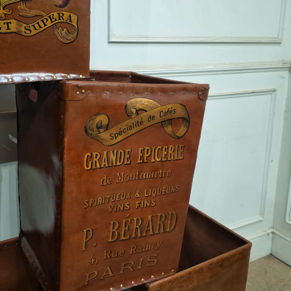 A collection of warm brown studded leather storage bins decorated with gilded French typography and heraldic crests. View IX