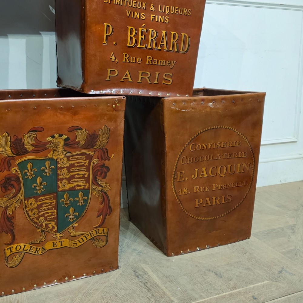 A collection of warm brown studded leather storage bins decorated with gilded French typography and heraldic crests. View XII