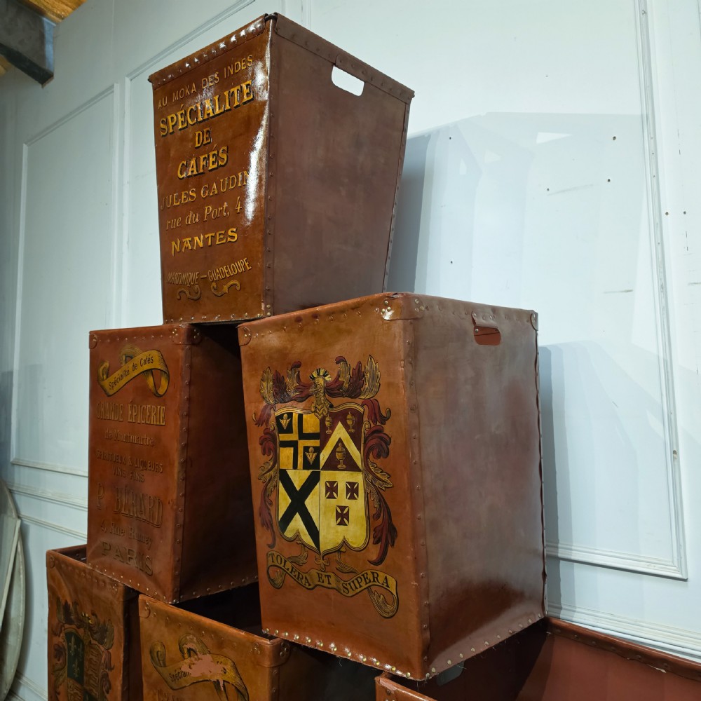 A collection of warm brown studded leather storage bins decorated with gilded French typography and heraldic crests. View XIII