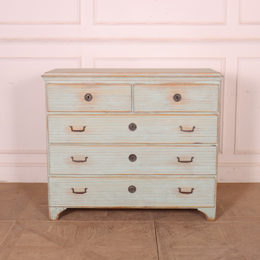 A Swedish painted pine commode featuring horizontal fluted drawer fronts, a pale blue distressed finish, and iron hardware.