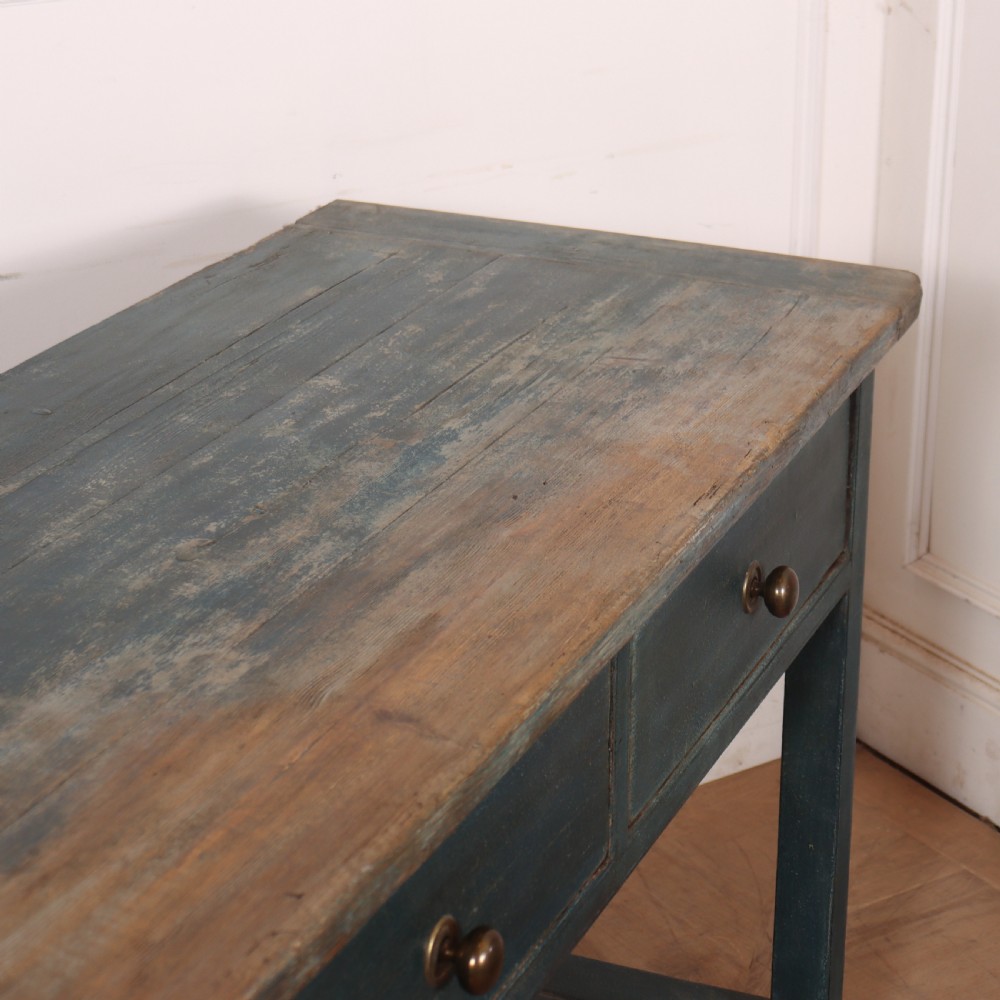 A long muted blue painted wooden dresser base featuring four drawers with brass knobs, a exposed wood top surface, and an open slatted lower shelf. View IX