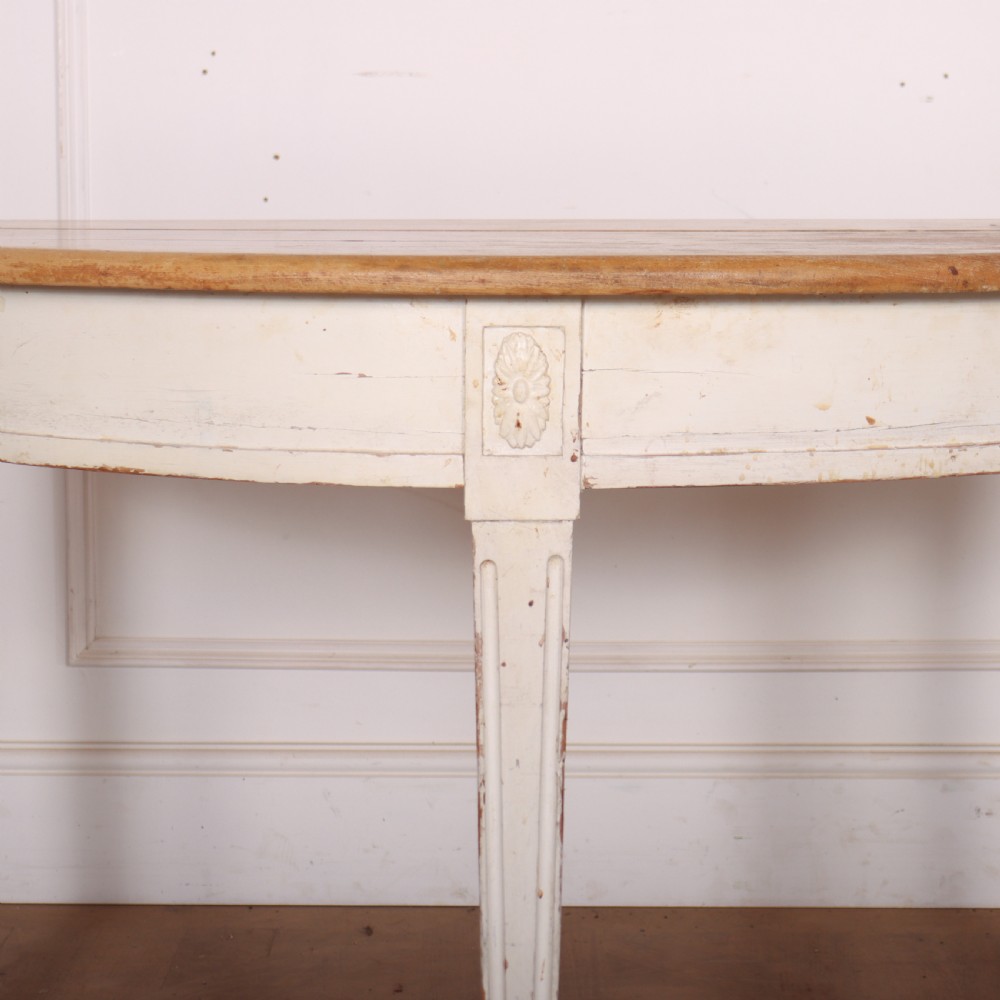 A Swedish demi-lune console table featuring a natural timber semicircular top, off-white painted apron with carved rosette detail, and fluted tapered legs. View II