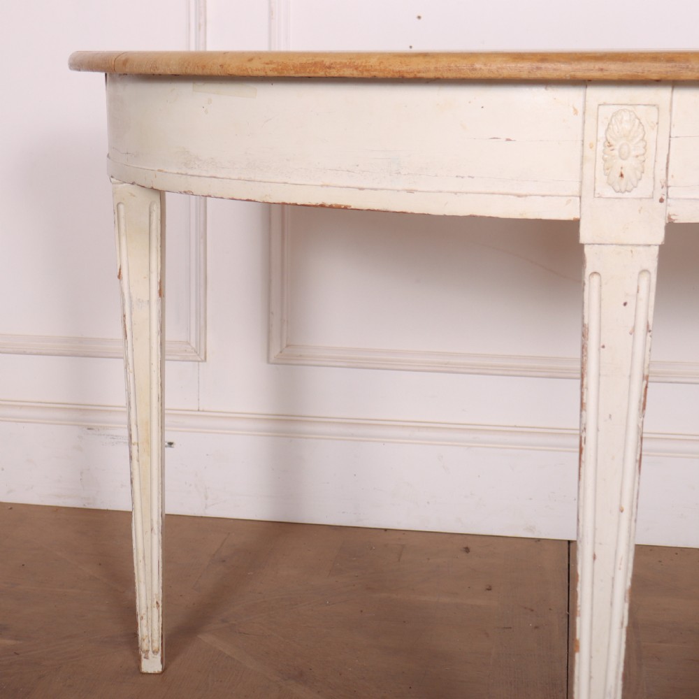 A Swedish demi-lune console table featuring a natural timber semicircular top, off-white painted apron with carved rosette detail, and fluted tapered legs. View III