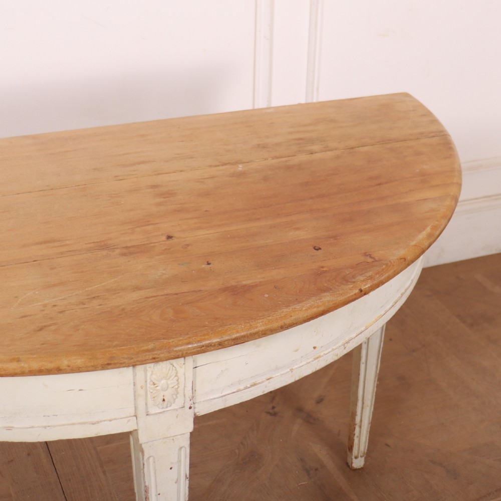 A Swedish demi-lune console table featuring a natural timber semicircular top, off-white painted apron with carved rosette detail, and fluted tapered legs. View V