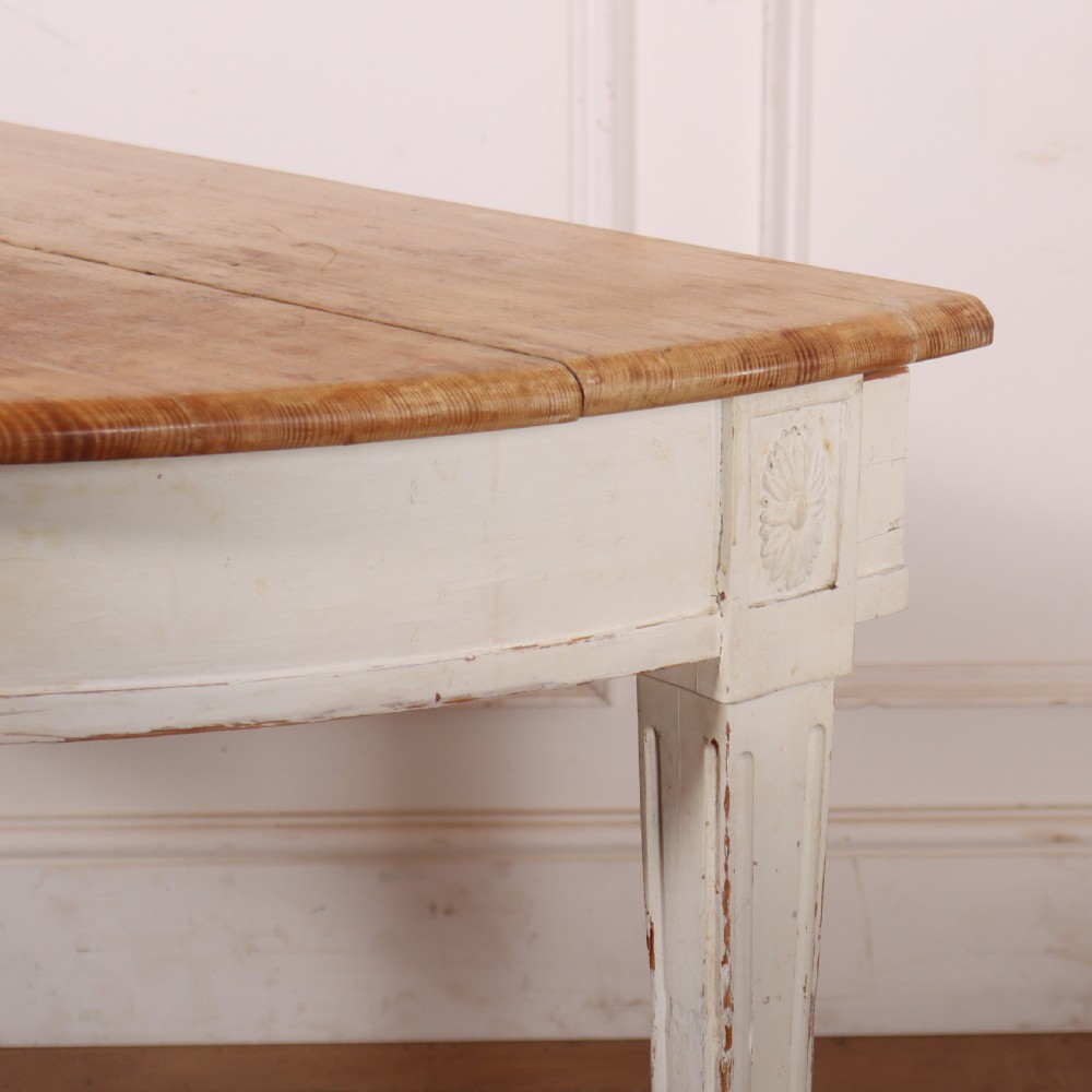 A Swedish demi-lune console table featuring a natural timber semicircular top, off-white painted apron with carved rosette detail, and fluted tapered legs. View VI