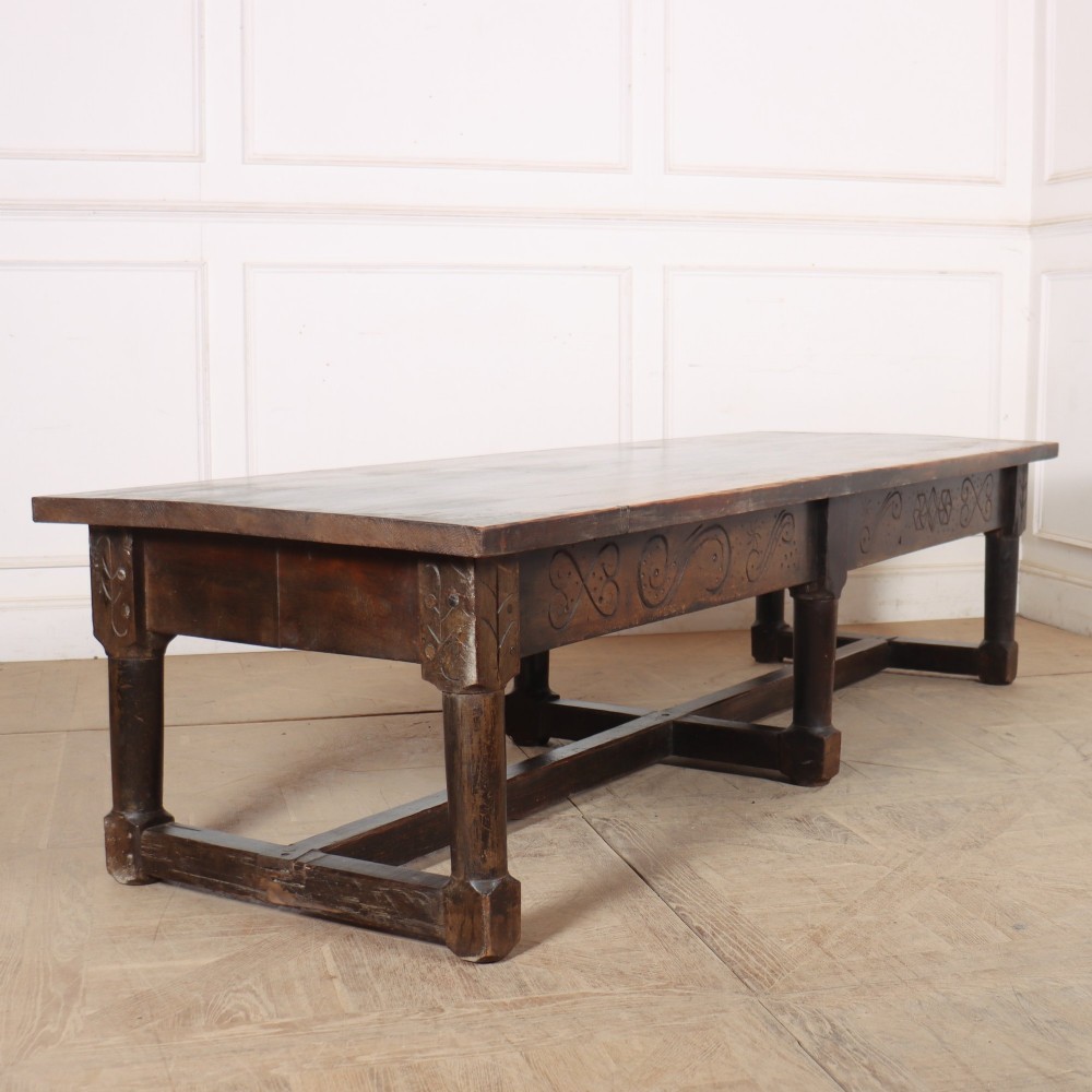 A large, low rectangular coffee table crafted from dark oak, featuring carved scroll patterns along the frieze and a sturdy stretcher base.
