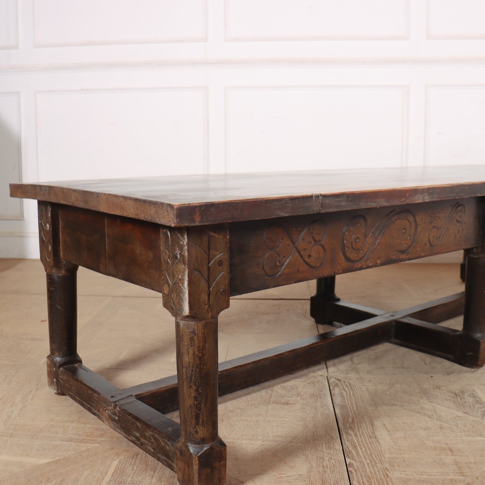 A large, low rectangular coffee table crafted from dark oak, featuring carved scroll patterns along the frieze and a sturdy stretcher base. View II