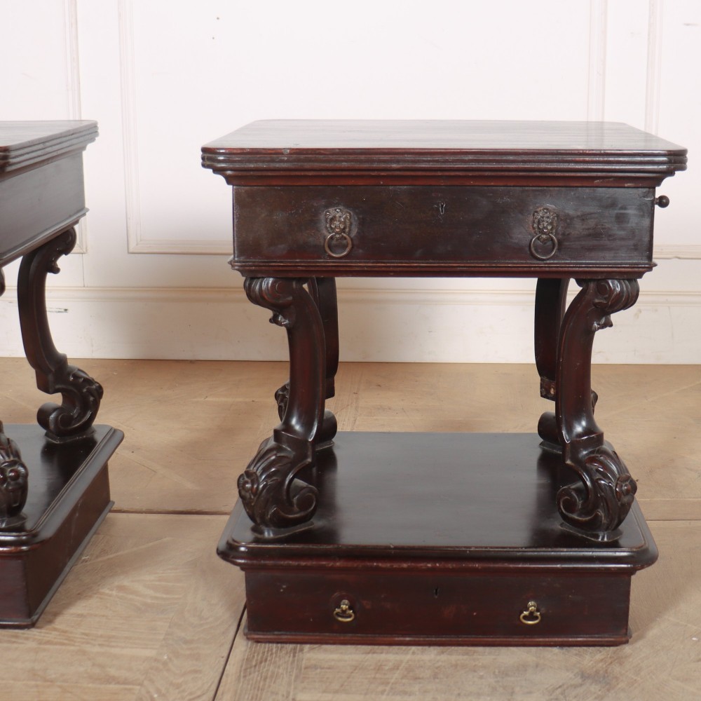 A pair of dark mahogany bedside tables featuring carved scroll supports, upper and lower drawers with brass drop-ring handles, resting on solid plinth bases. View VII