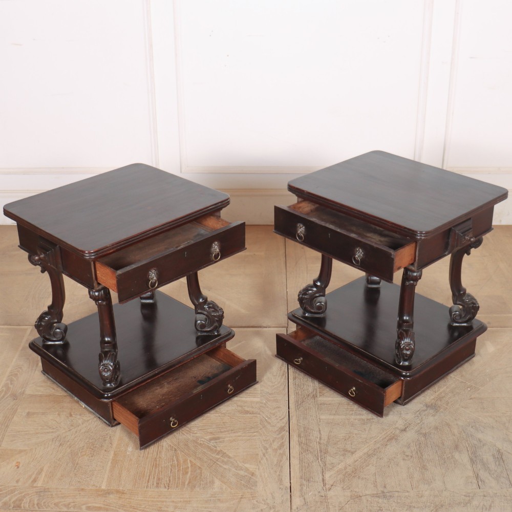 A pair of dark mahogany bedside tables featuring carved scroll supports, upper and lower drawers with brass drop-ring handles, resting on solid plinth bases. View XI