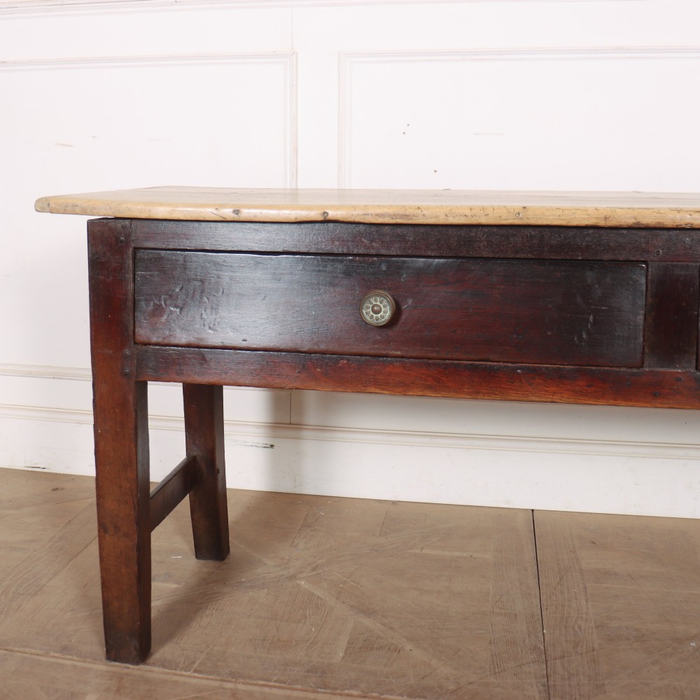 A dark-stained Welsh oak dresser base featuring two wide drawers with circular knobs and a light scrubbed timber top surface. View II