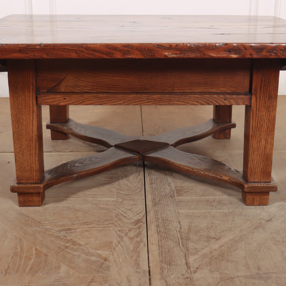 A rectangular warm brown solid elm coffee table with a thick plank top and a distinctive X-shaped lower stretcher base. View II