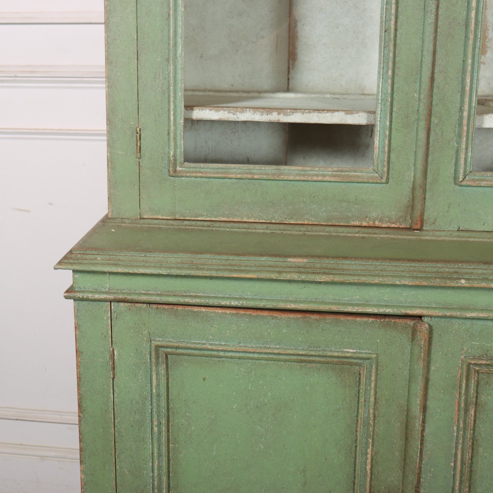 A large sage green painted wooden kitchen dresser with three upper glazed cabinet doors and three lower solid panelled doors. View III