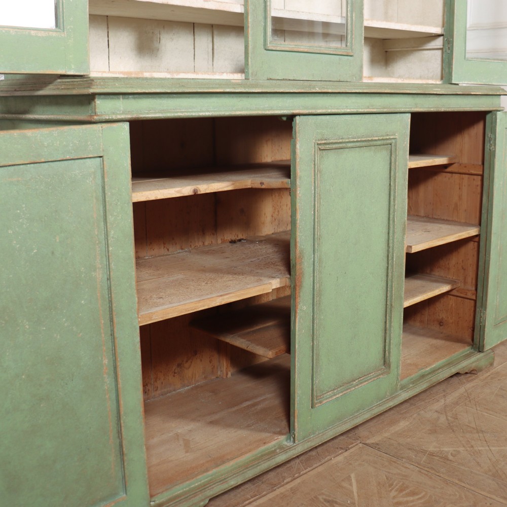 A large sage green painted wooden kitchen dresser with three upper glazed cabinet doors and three lower solid panelled doors. View XI