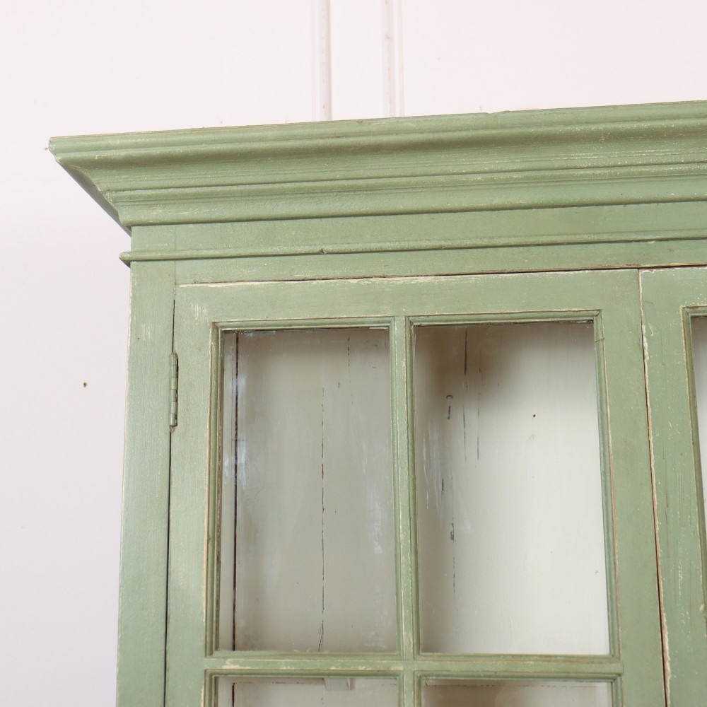A tall 19th-century English glazed bookcase painted in sage green featuring twin multi-pane glass doors and a white painted interior. View II