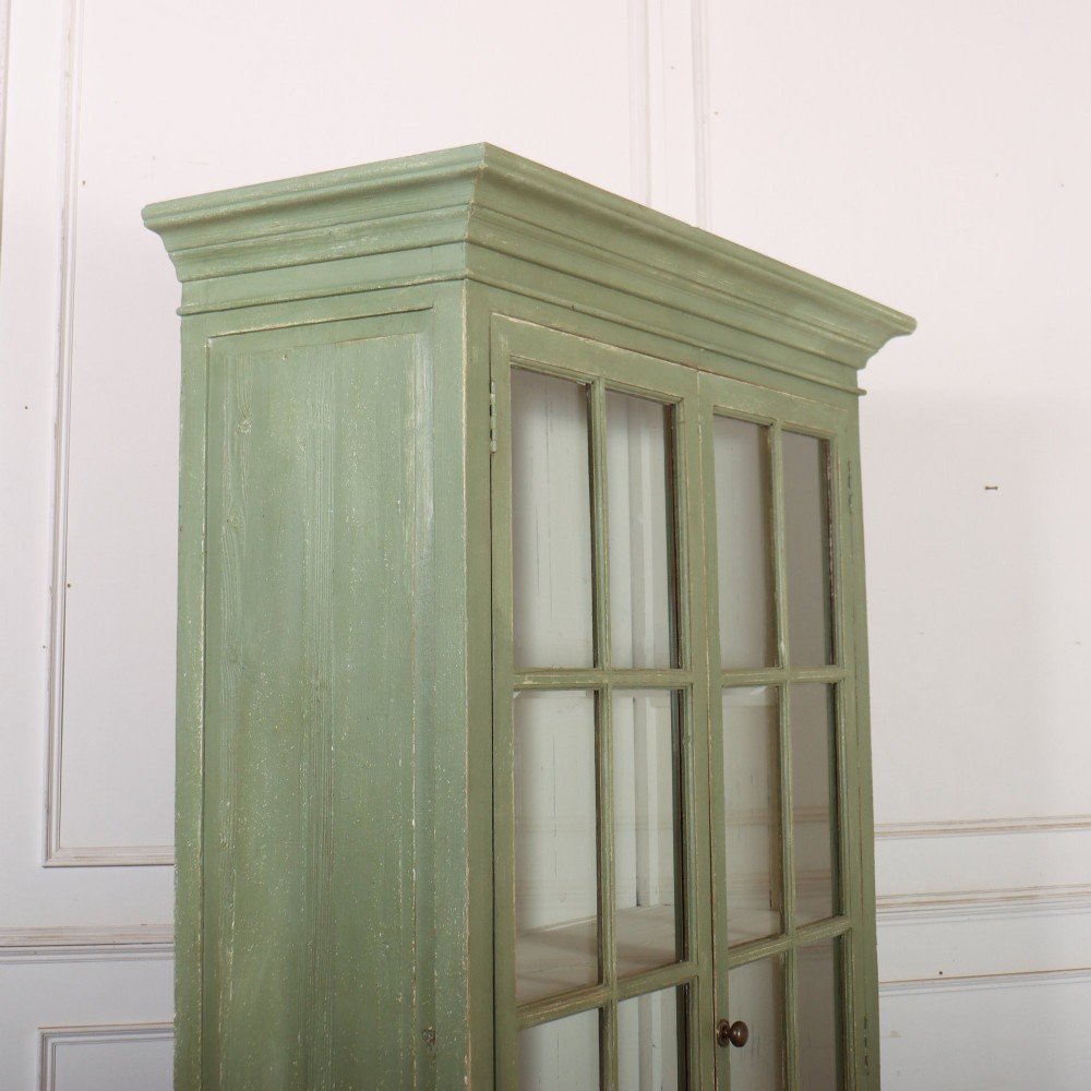 A tall 19th-century English glazed bookcase painted in sage green featuring twin multi-pane glass doors and a white painted interior. View X