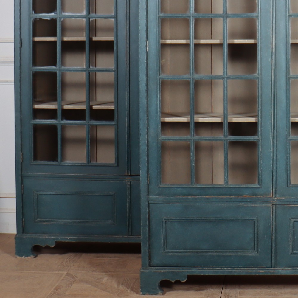 A pair of tall painted teal blue wooden library bookcases with multi-pane glazed doors, moulded cornices, and lower paneled drawers. View II