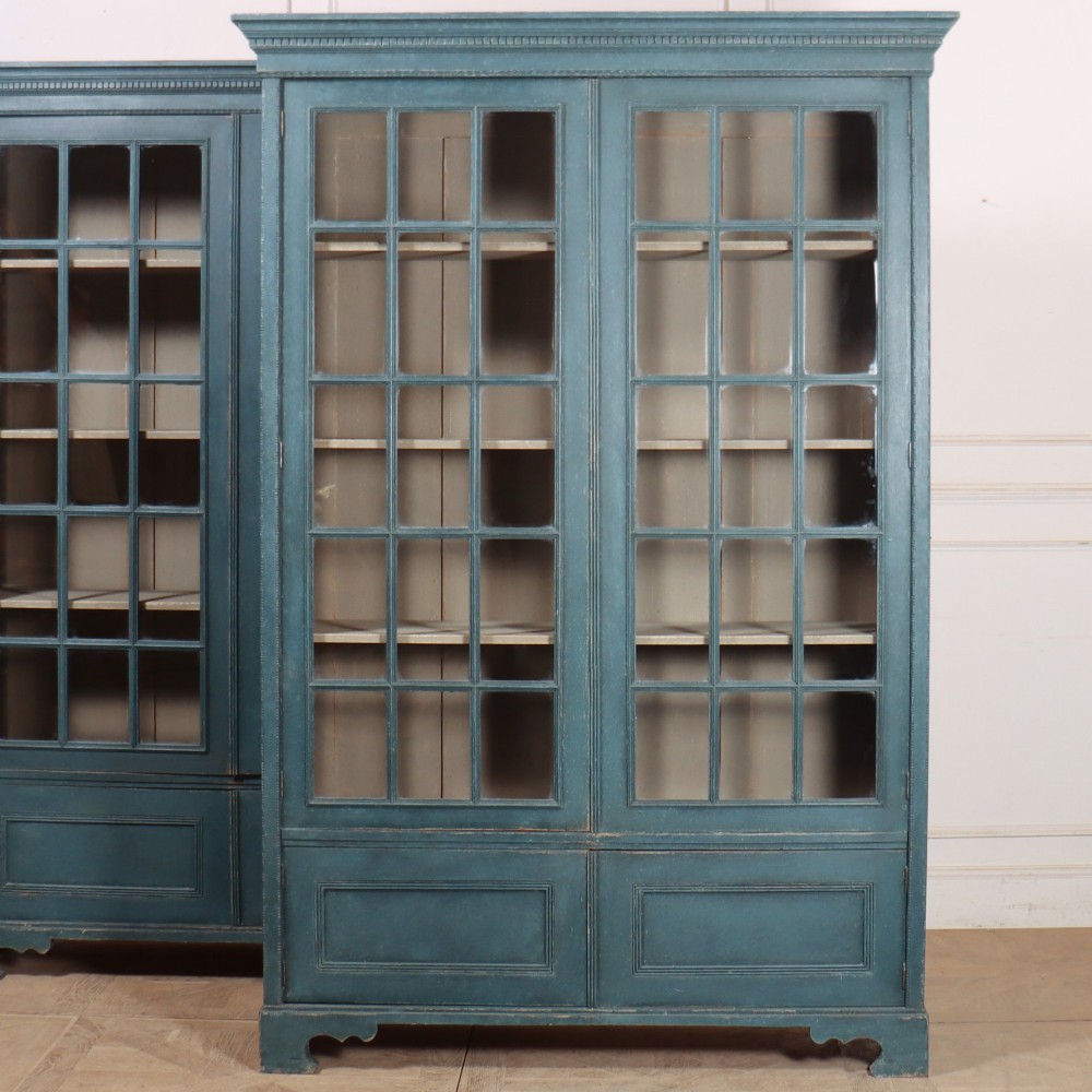 A pair of tall painted teal blue wooden library bookcases with multi-pane glazed doors, moulded cornices, and lower paneled drawers. View III