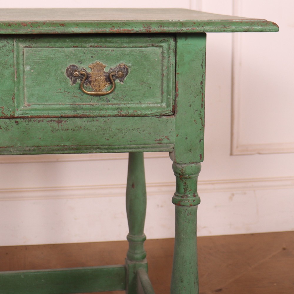 An antique English oak lamp table featuring a distressed green painted finish, two drawers with brass handles, turned legs, and a lower stretcher base. View III