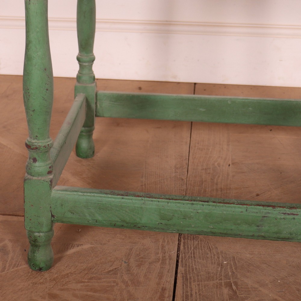 An antique English oak lamp table featuring a distressed green painted finish, two drawers with brass handles, turned legs, and a lower stretcher base. View V
