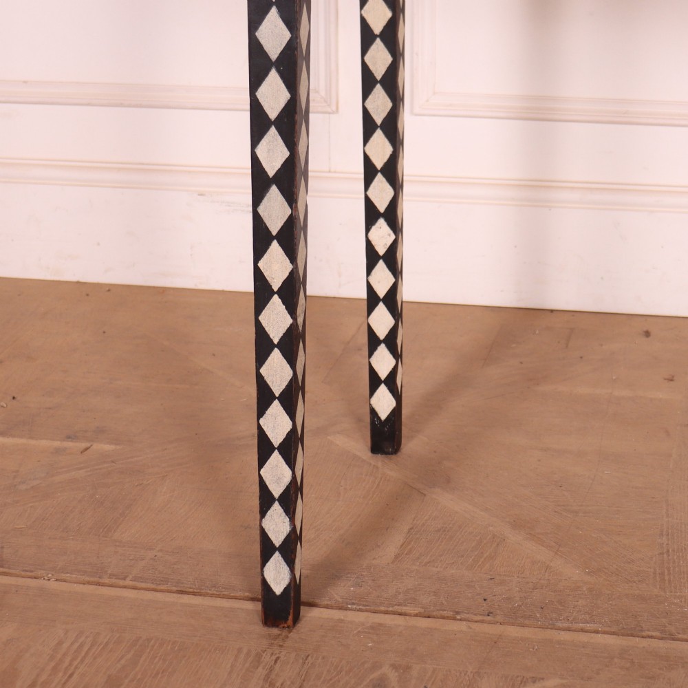 A rectangular black painted lamp table featuring a hand-painted cream and black harlequin diamond pattern on the front drawer and square legs, finished with two brass ring pull handles. View V