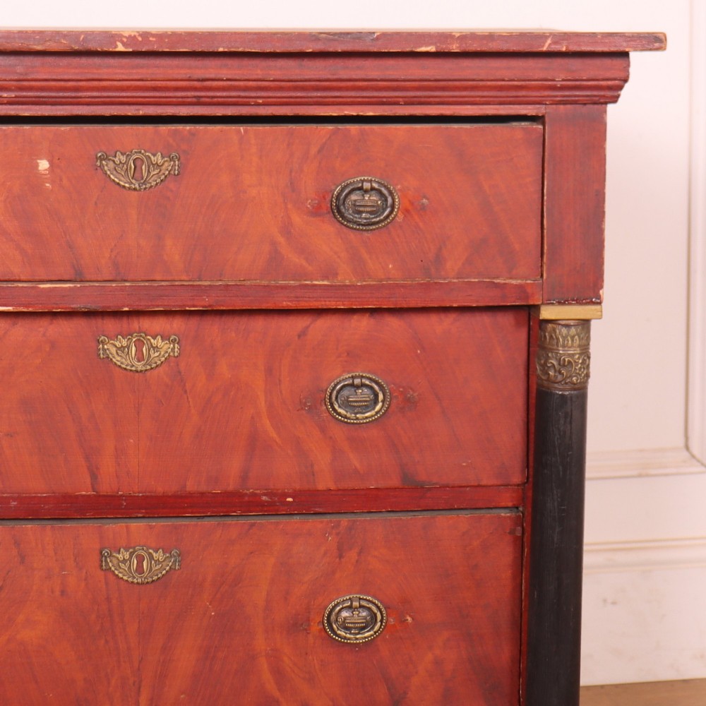 A Dutch Empire style red mahogany commode with four drawers, ebonised side columns, and round brass handles. View III