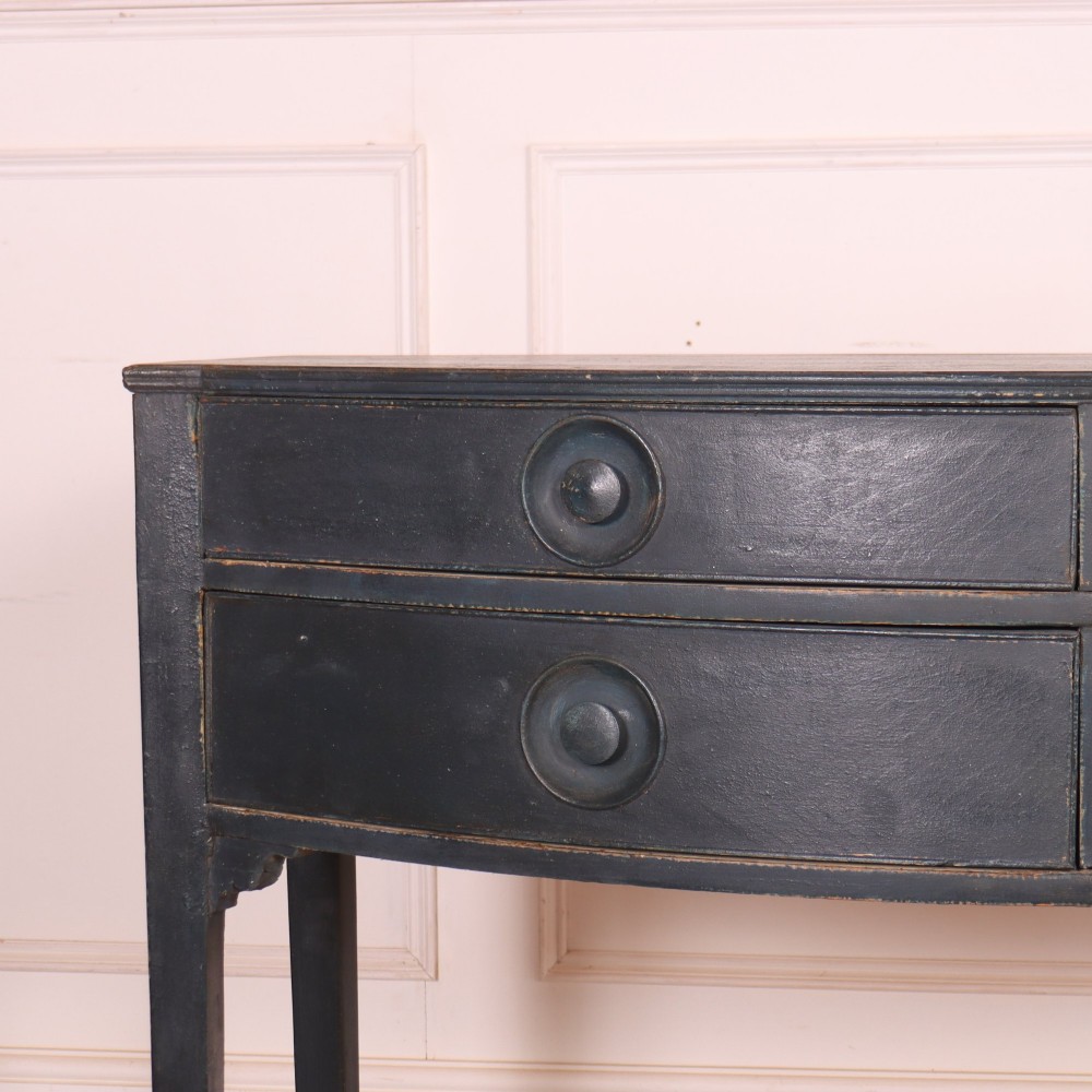 A dark painted antique bowfront console table featuring four drawers with circular wooden knob handles and slender square tapered legs. View II