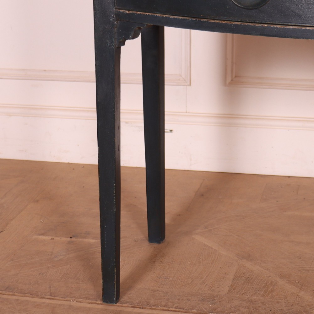 A dark painted antique bowfront console table featuring four drawers with circular wooden knob handles and slender square tapered legs. View V