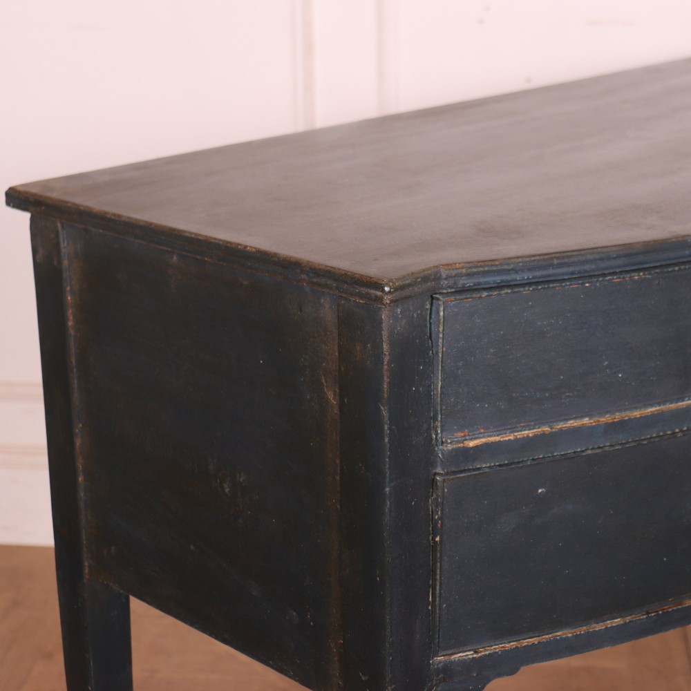 A dark painted antique bowfront console table featuring four drawers with circular wooden knob handles and slender square tapered legs. View VII