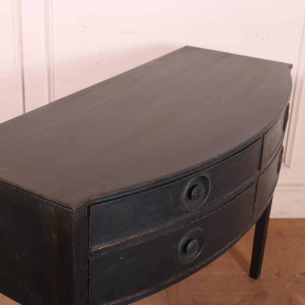 A dark painted antique bowfront console table featuring four drawers with circular wooden knob handles and slender square tapered legs. View VIII