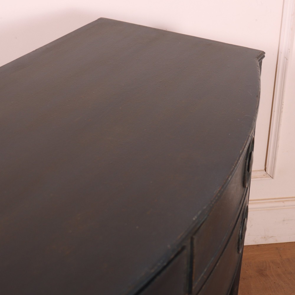 A dark painted antique bowfront console table featuring four drawers with circular wooden knob handles and slender square tapered legs. View IX
