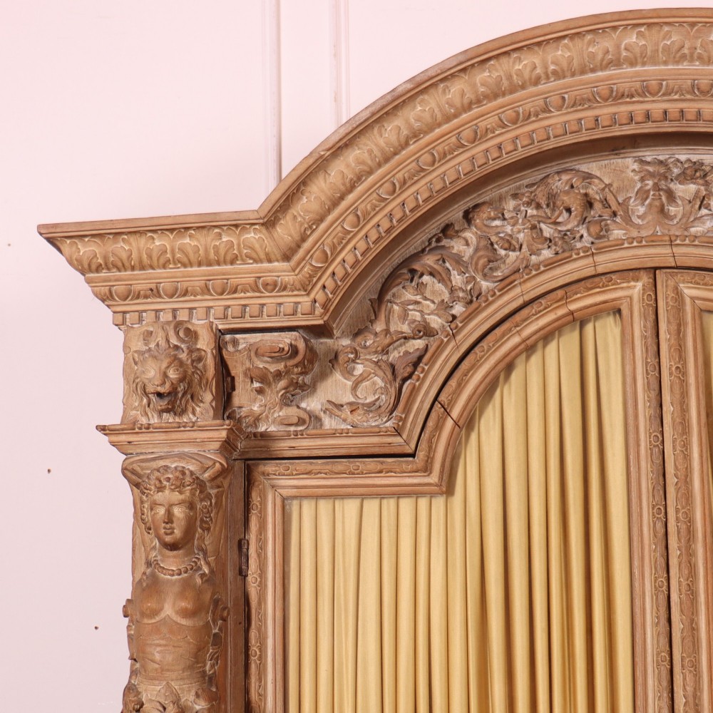 A large Italian carved wood vitrine featuring arched upper glazed doors lined with fabric, flanked by caryatid figures and intricate relief panels. View II