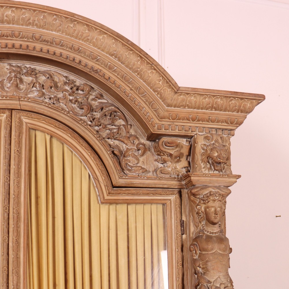 A large Italian carved wood vitrine featuring arched upper glazed doors lined with fabric, flanked by caryatid figures and intricate relief panels. View IV