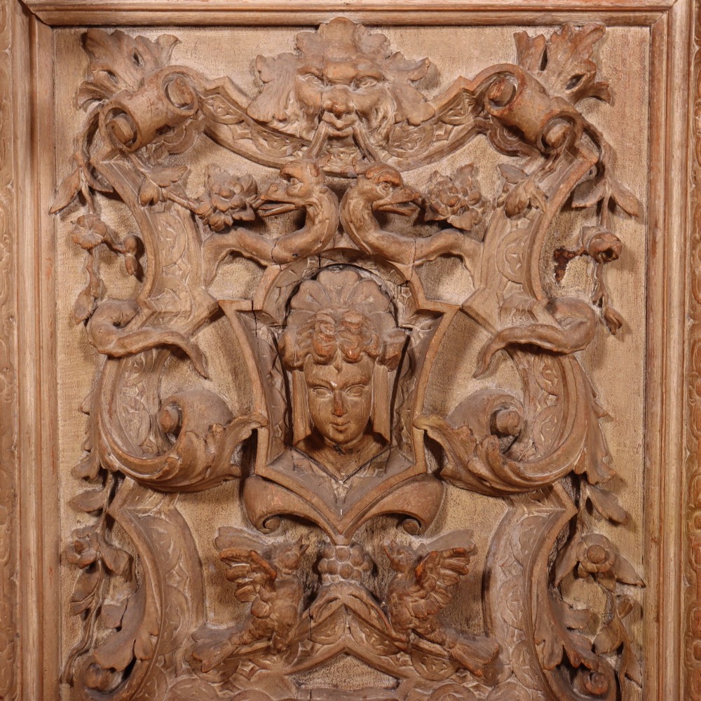 A large Italian carved wood vitrine featuring arched upper glazed doors lined with fabric, flanked by caryatid figures and intricate relief panels. View IX