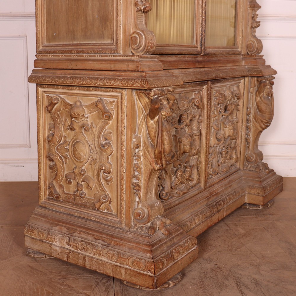 A large Italian carved wood vitrine featuring arched upper glazed doors lined with fabric, flanked by caryatid figures and intricate relief panels. View XIII
