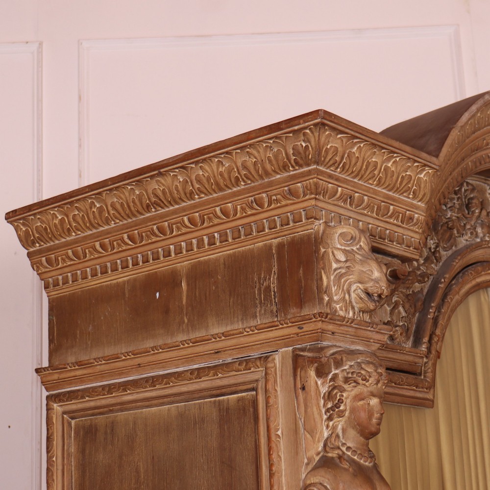 A large Italian carved wood vitrine featuring arched upper glazed doors lined with fabric, flanked by caryatid figures and intricate relief panels. View XIV