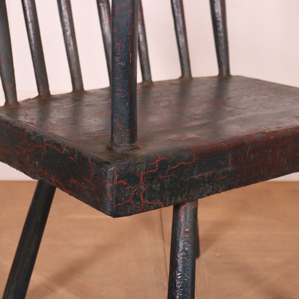 An antique dark green painted Irish primitive armchair featuring a thick wooden slab seat, spindle backrest, flat armrests, and splayed legs. View II