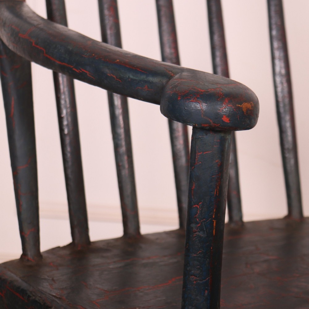 An antique dark green painted Irish primitive armchair featuring a thick wooden slab seat, spindle backrest, flat armrests, and splayed legs. View III