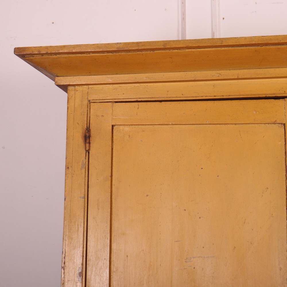 A large antique yellow-painted housekeeper cupboard featuring three upper cupboard doors above an arrangement of drawers and lower cupboards. View III